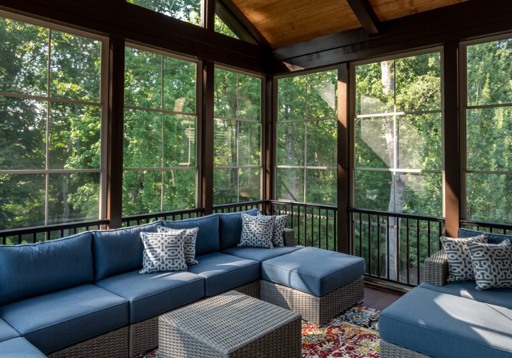 Screened porch with blue sectional sofa.